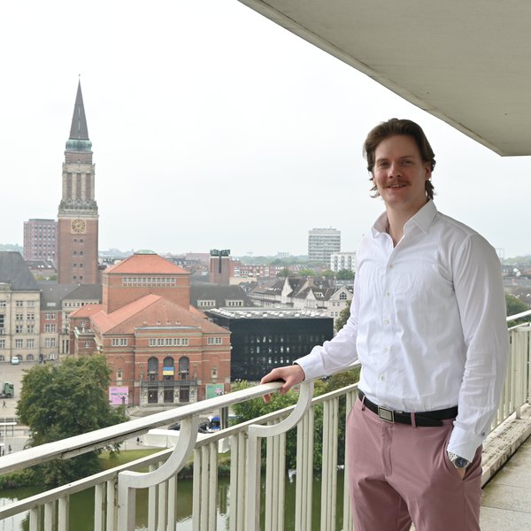 Hansen steht auf der Dachterasse mit Blick auf das Kieler Rathaus.