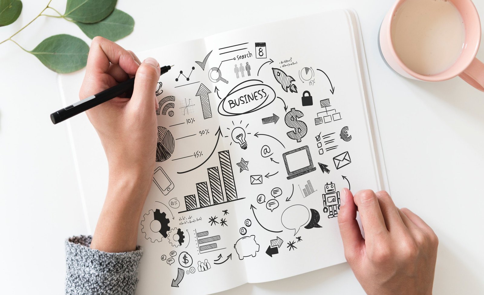 Hände über einem Sketchbook, die eine hält einen Stift, die andere das Heft.