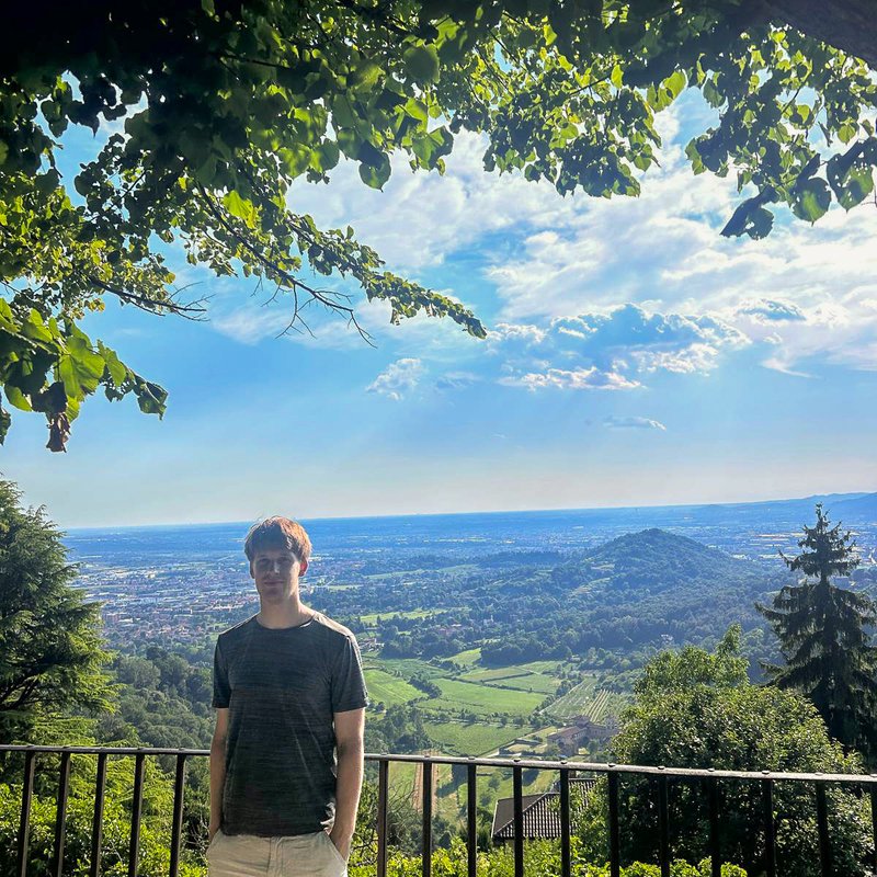 Tim Binder steht vor einem Panorama und blickt in die Kamera.