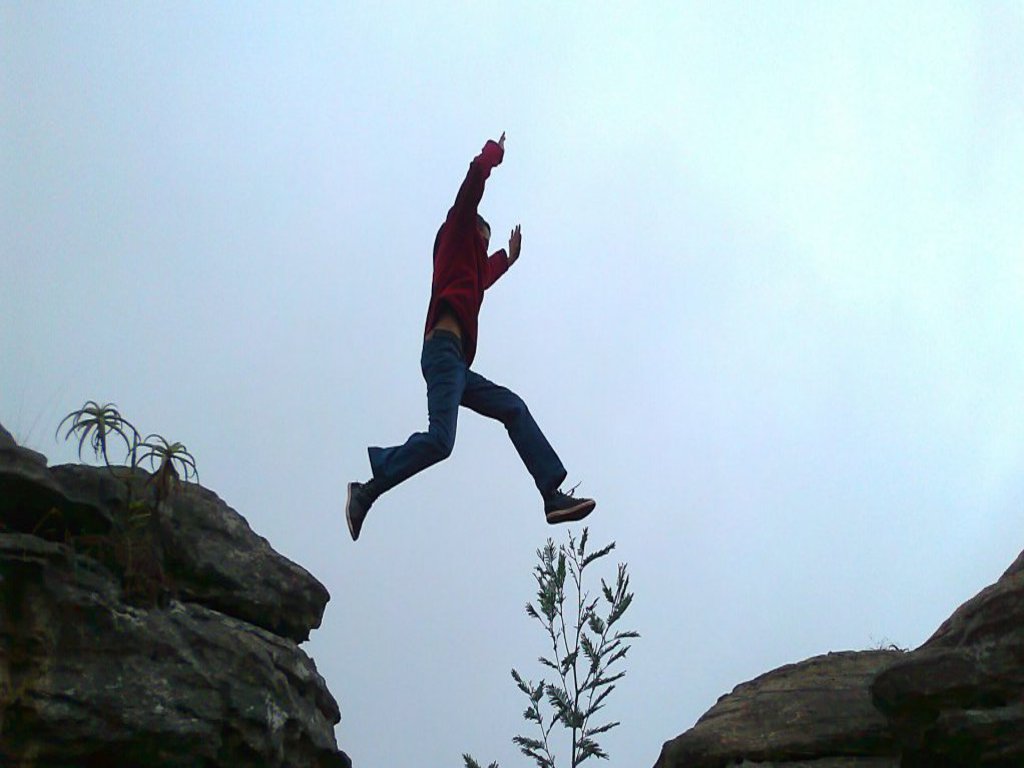 Eine Person springt von einem Felsen zu einem anderen.