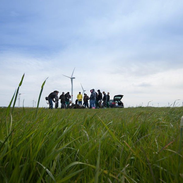 Menschen auf einem Feld mit Windkraftanlagen