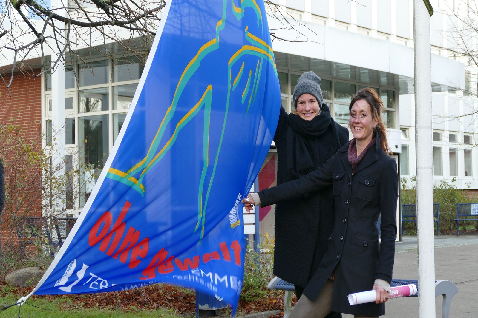 Wei Frauen präsentieren eine blaue Fahne.