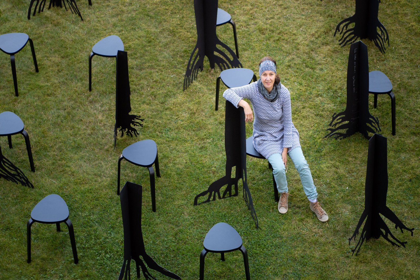 eine Frau auf einem Stuhl neben vielen anderen Stühlen
