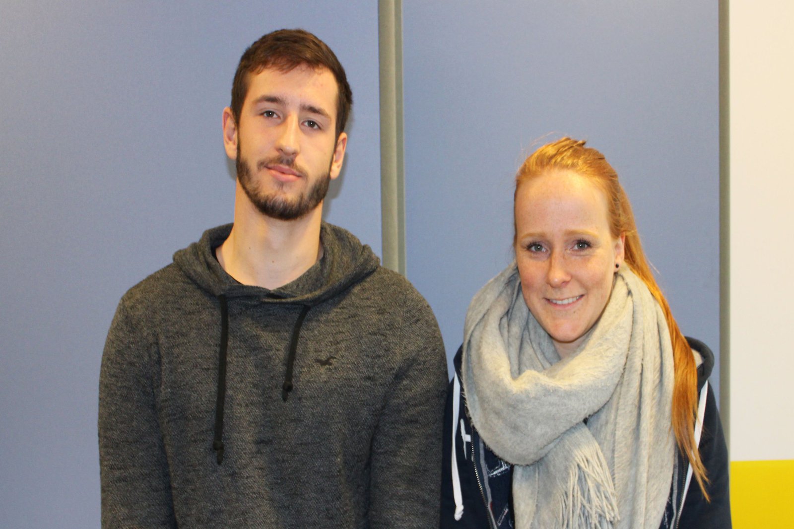 Ein Mann und eine Frau posieren vor einem hellblauen Hintergrund.