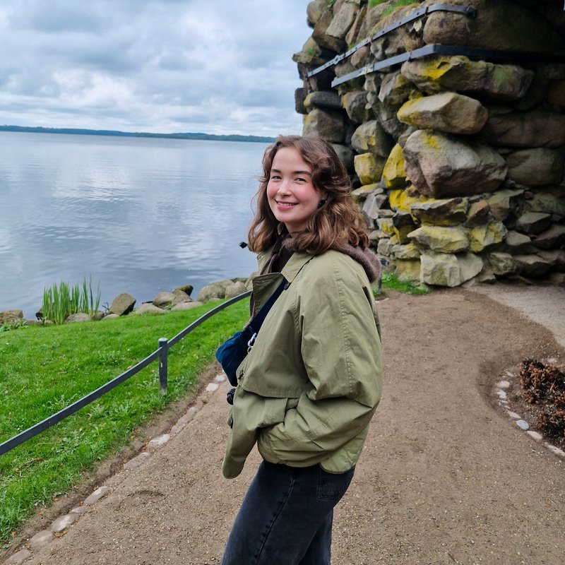 Polina stands in front of a rock face and smiles.