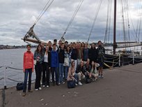 eine Gruppe Menschen vor einem Segelschiff