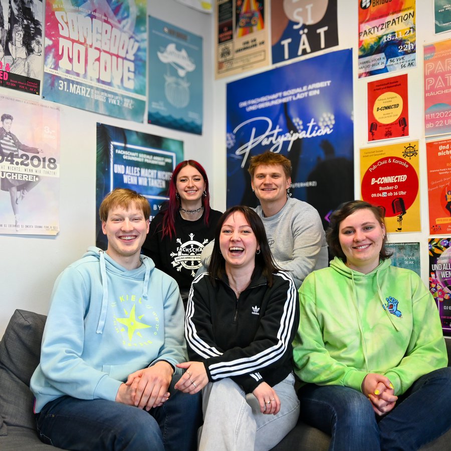 Fünf Mitglieder der Faschaft sitzen lachend auf dem Sofa.