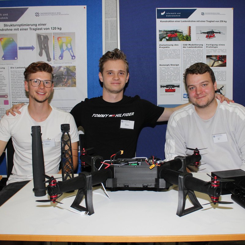 drei Studenten sitzen hinter ihren Drohnen an einem Tisch bei der Museumsnach 2025 an der FH Kiel