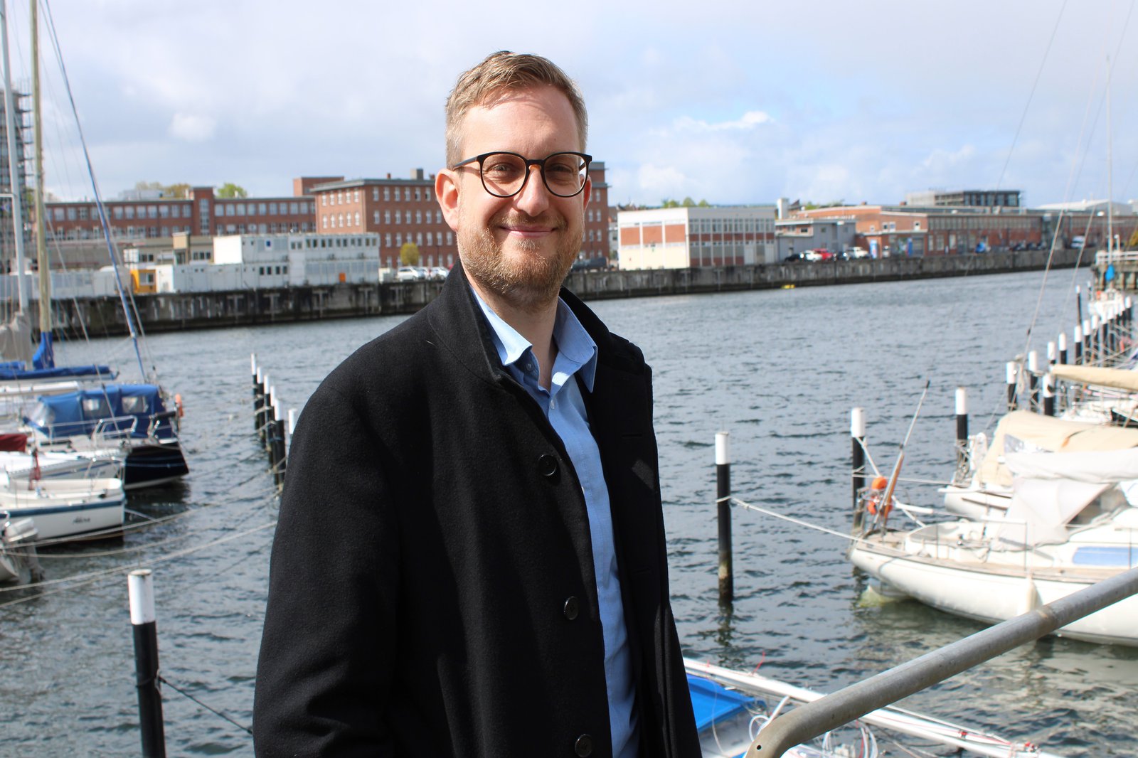 ein Mann in Jacke steht an der Schwentine in Kiel und blickt in die Kamera