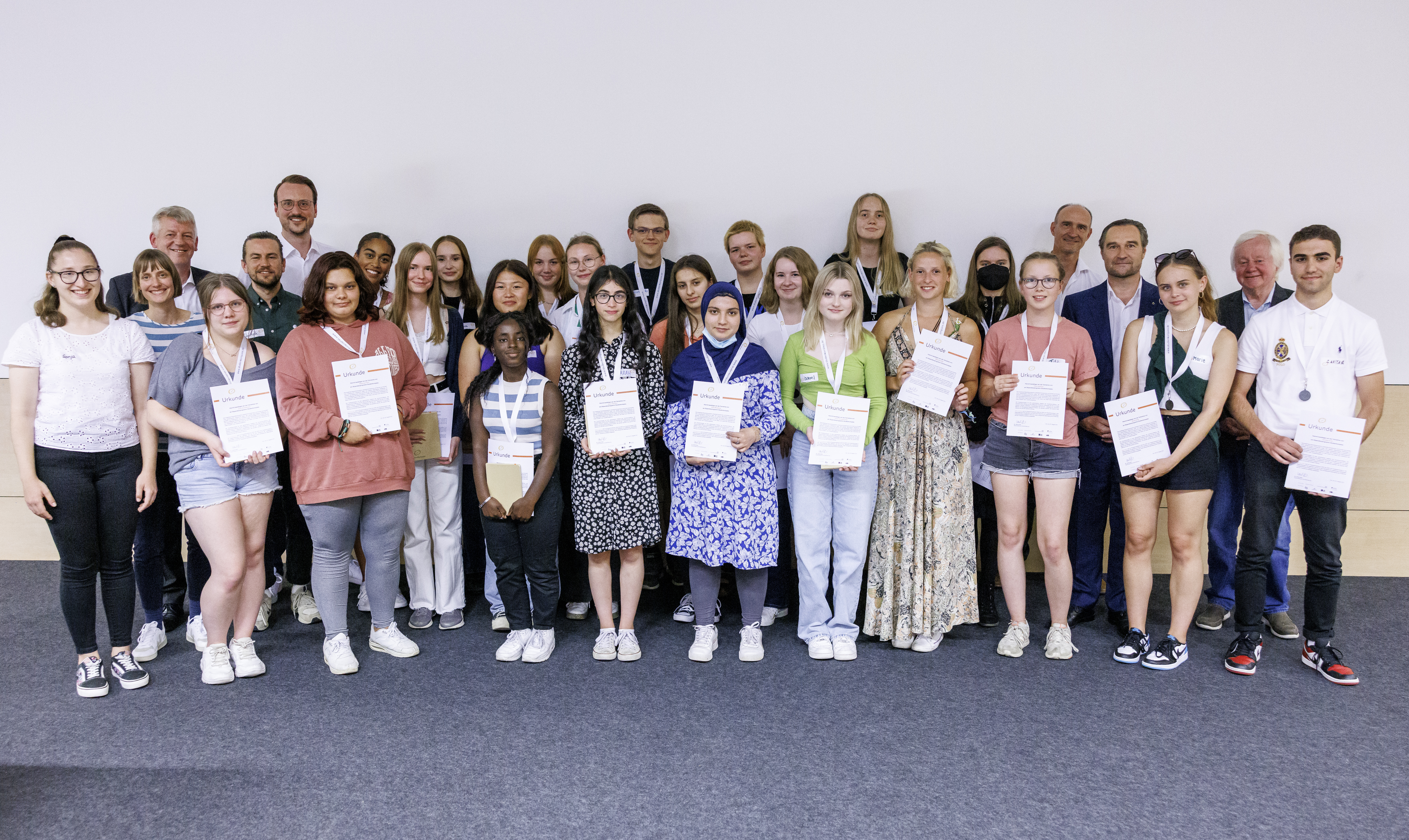 Eine Gruppe Menschen, viele halten Urkunden in ihren Händen