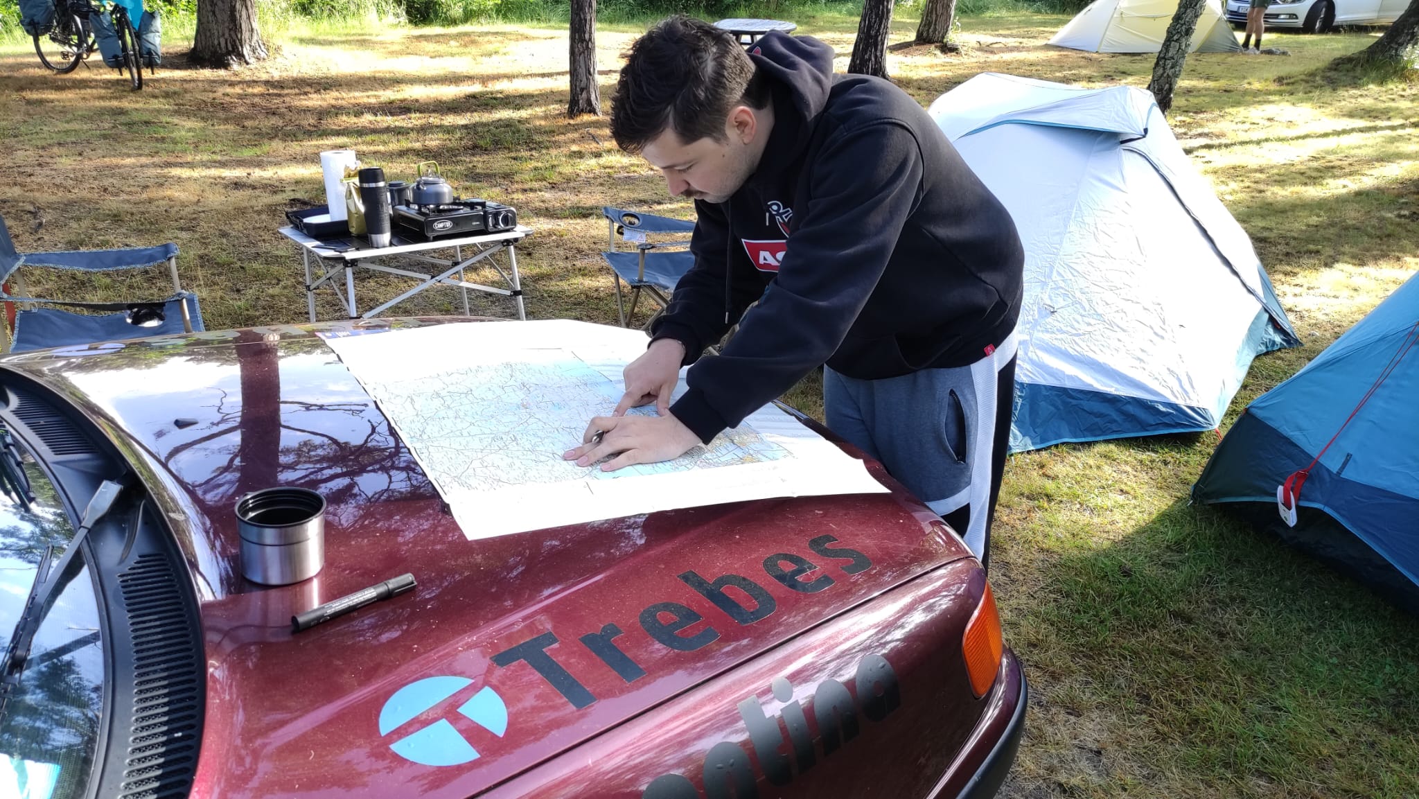 ein Mann mit einer Landkarte, die auf einer Motorhaube liegt