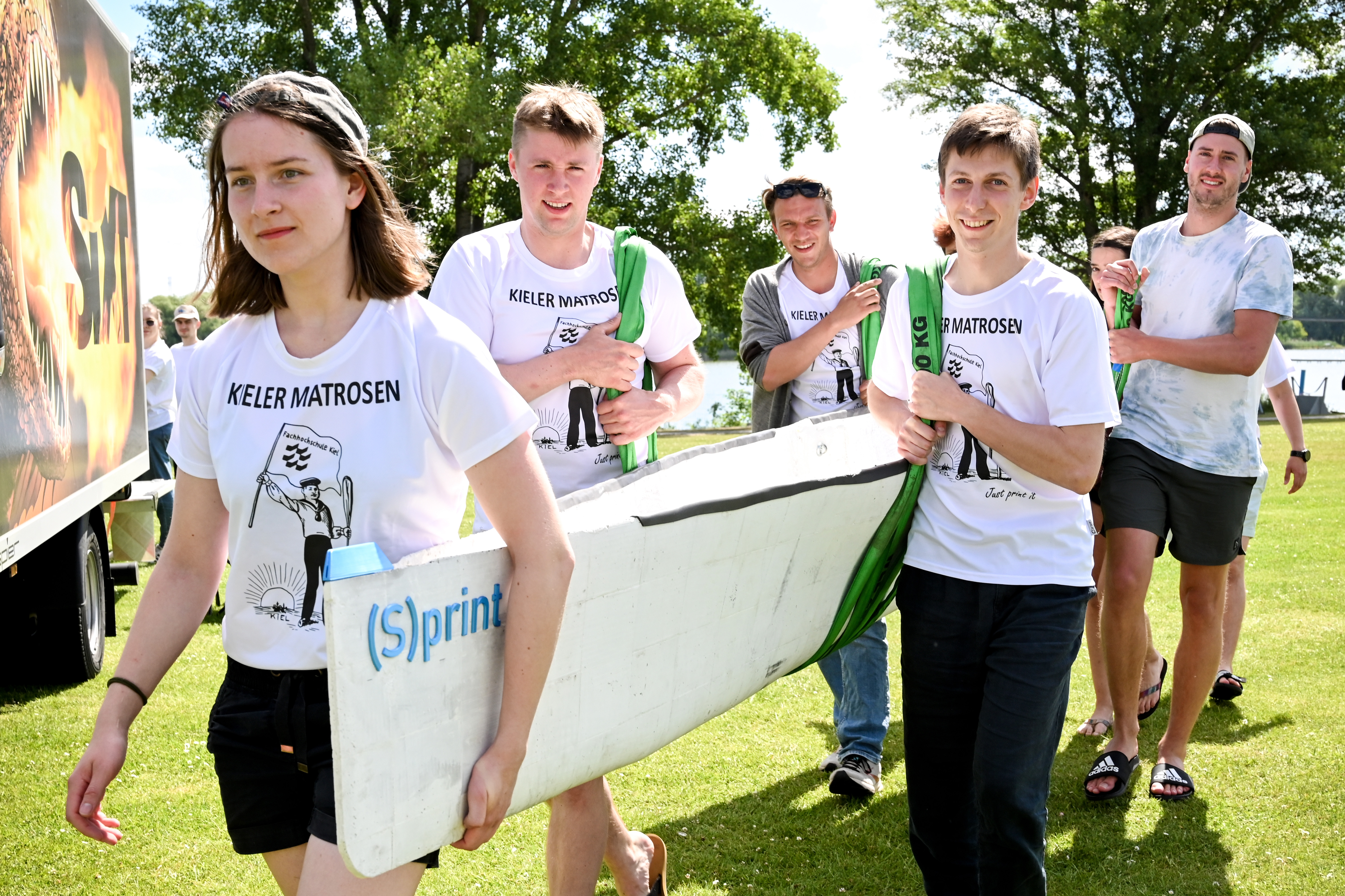 fünf Studierende, die ein Boot tragen