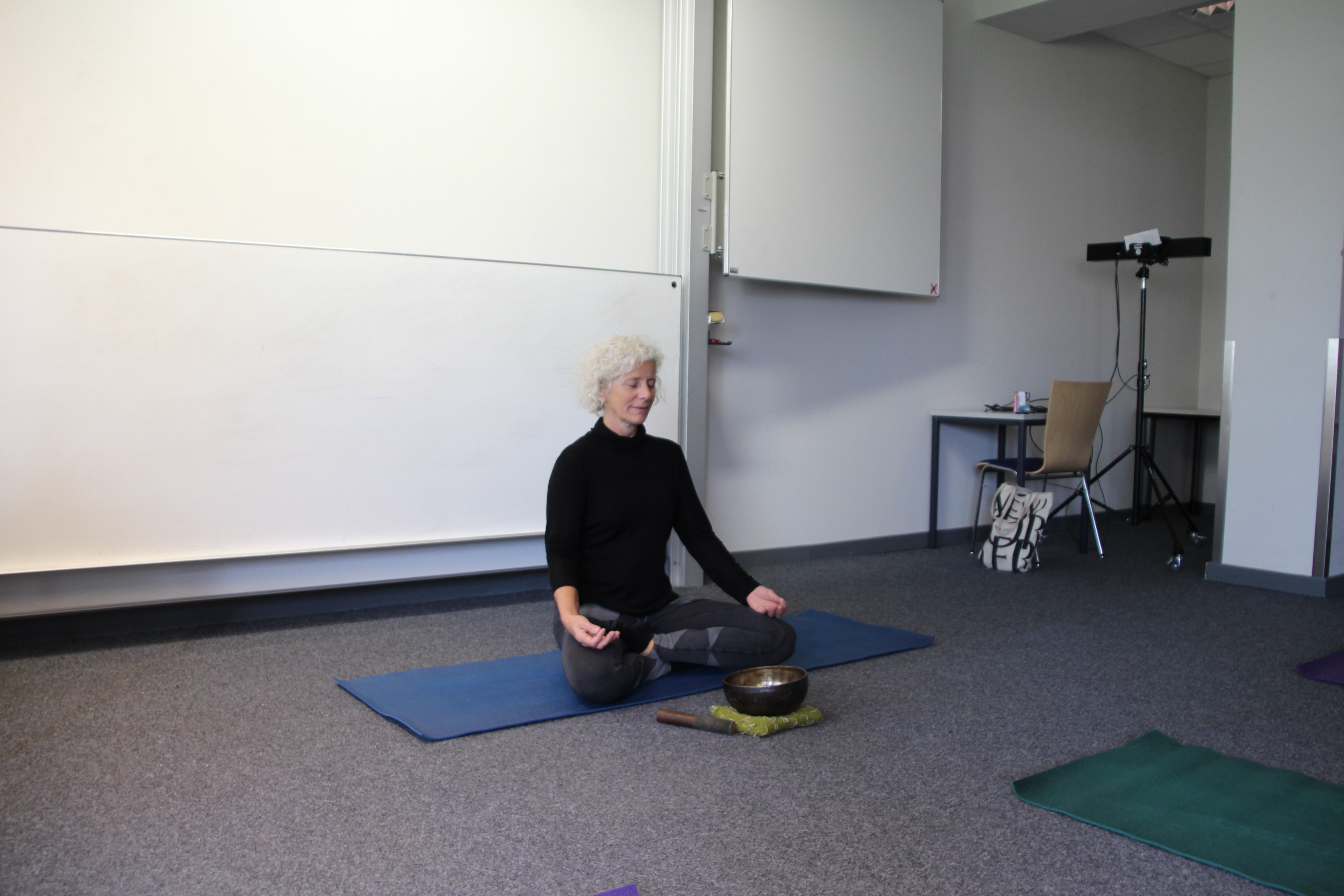 Eine Yoga-Lehrerin sitzt mit geschlossenen Augen auf ihrer Yogamatte