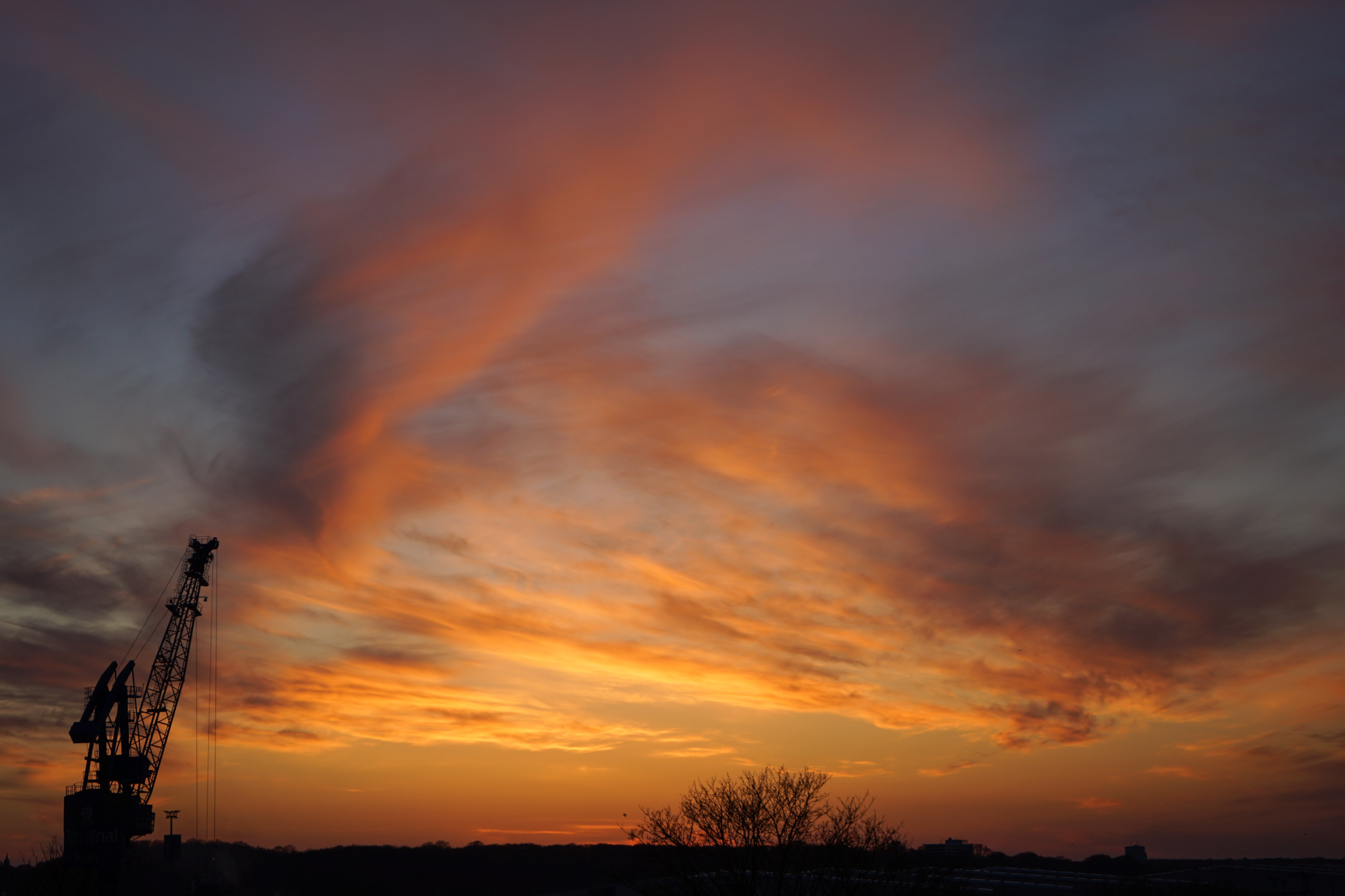Dramatischer Sonnenuntergang, links im Bild ein Kran
