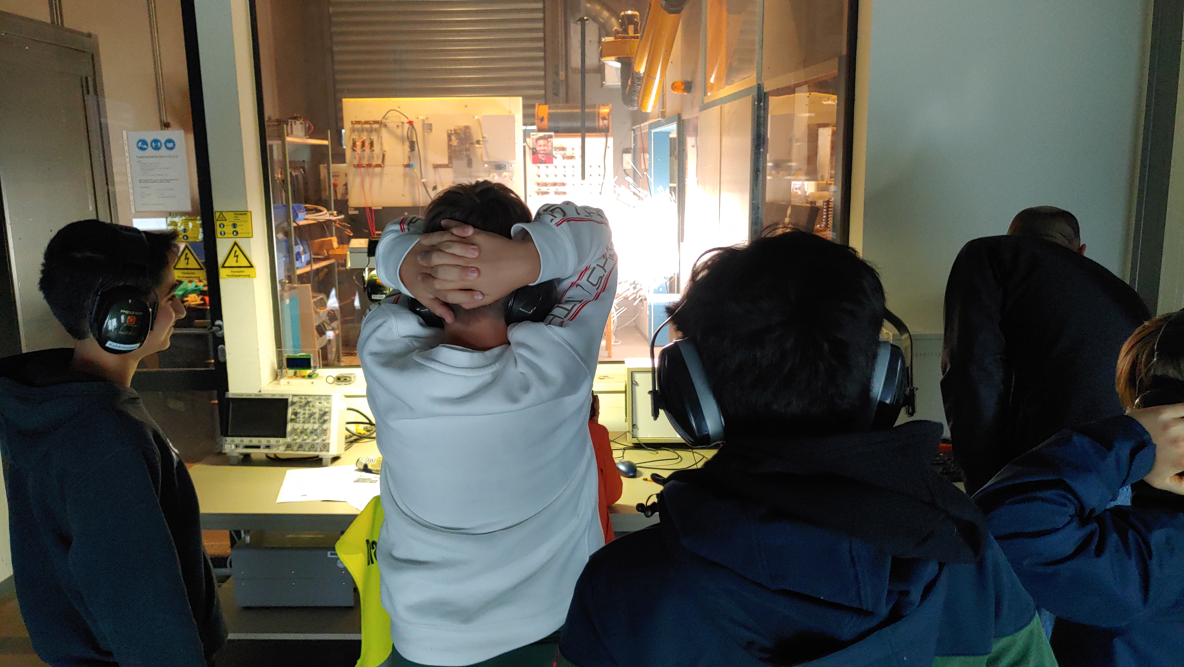 vier Personen blicken in das Hochspannungslabor der FH Kiel