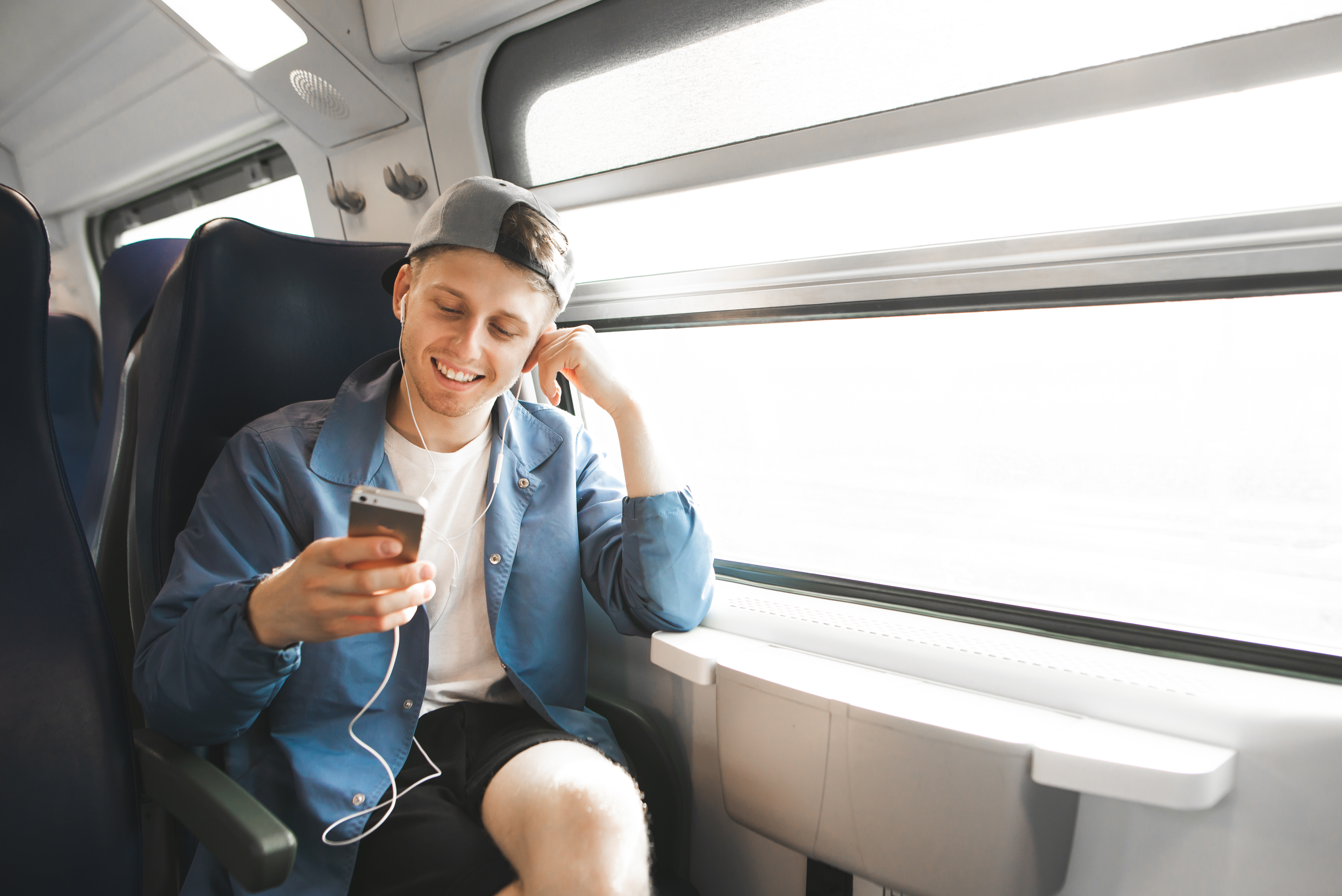 Smiling tourists travel by train and listens to music in the hea ein junger Mann in einem Zug