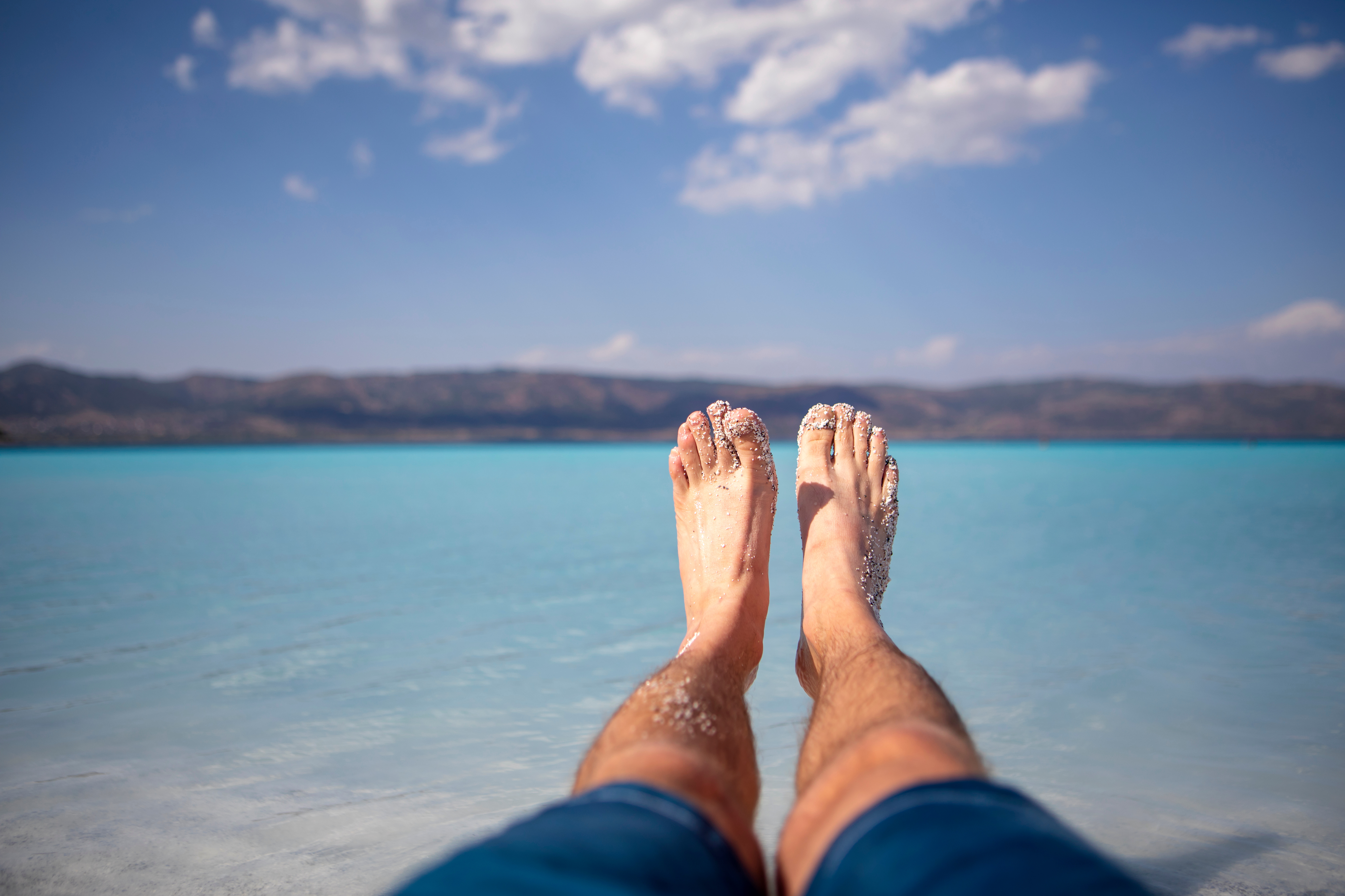 Man foot at summer blue beach Füße am Meer