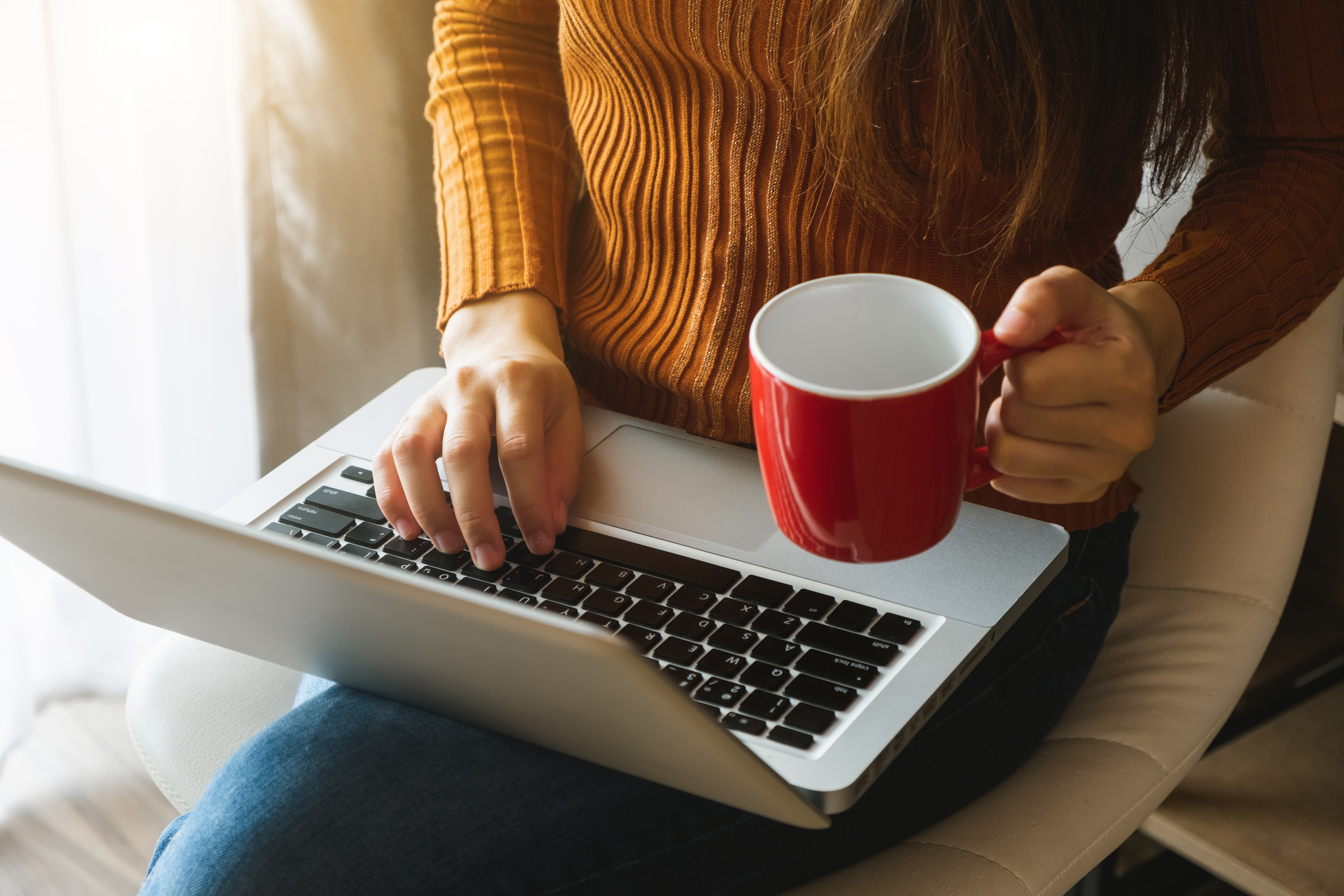 womman using laptop and typing and holding coffee cup in cafe, h Frau mit Laptop und Tasse