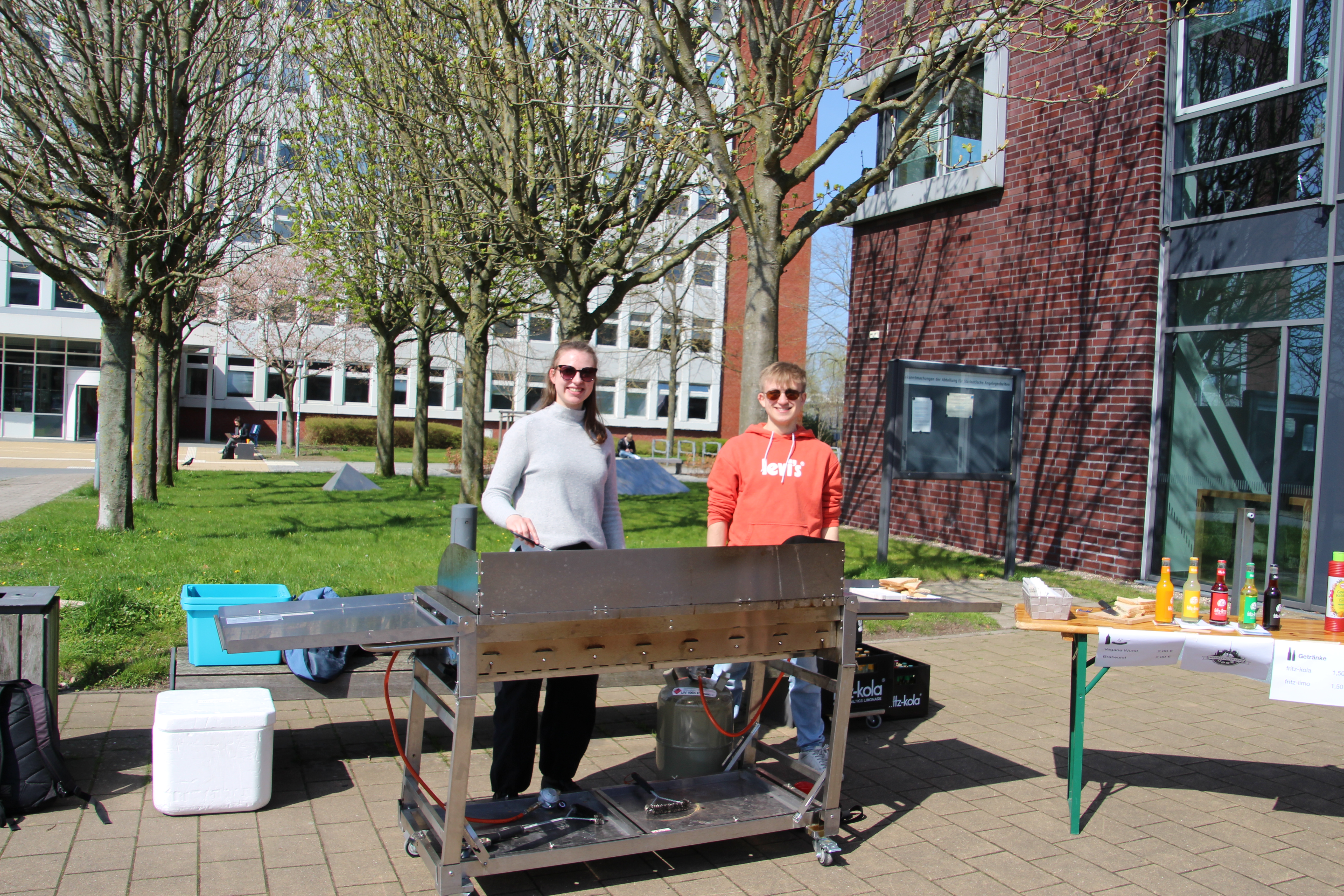 zwei Menschen stehen hinter einem Grill