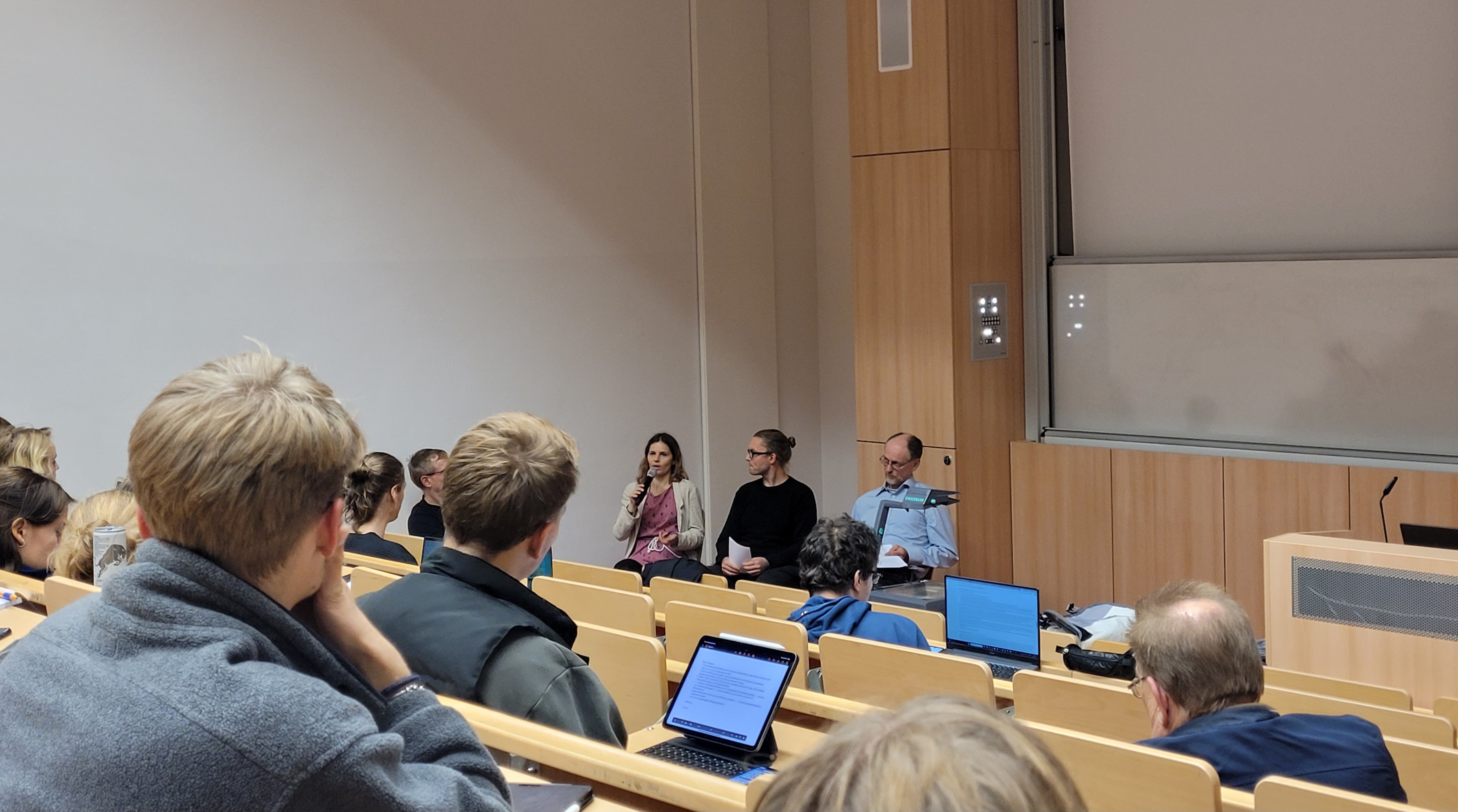 Personen sitzen auf Stühlen in einem Hörsaal