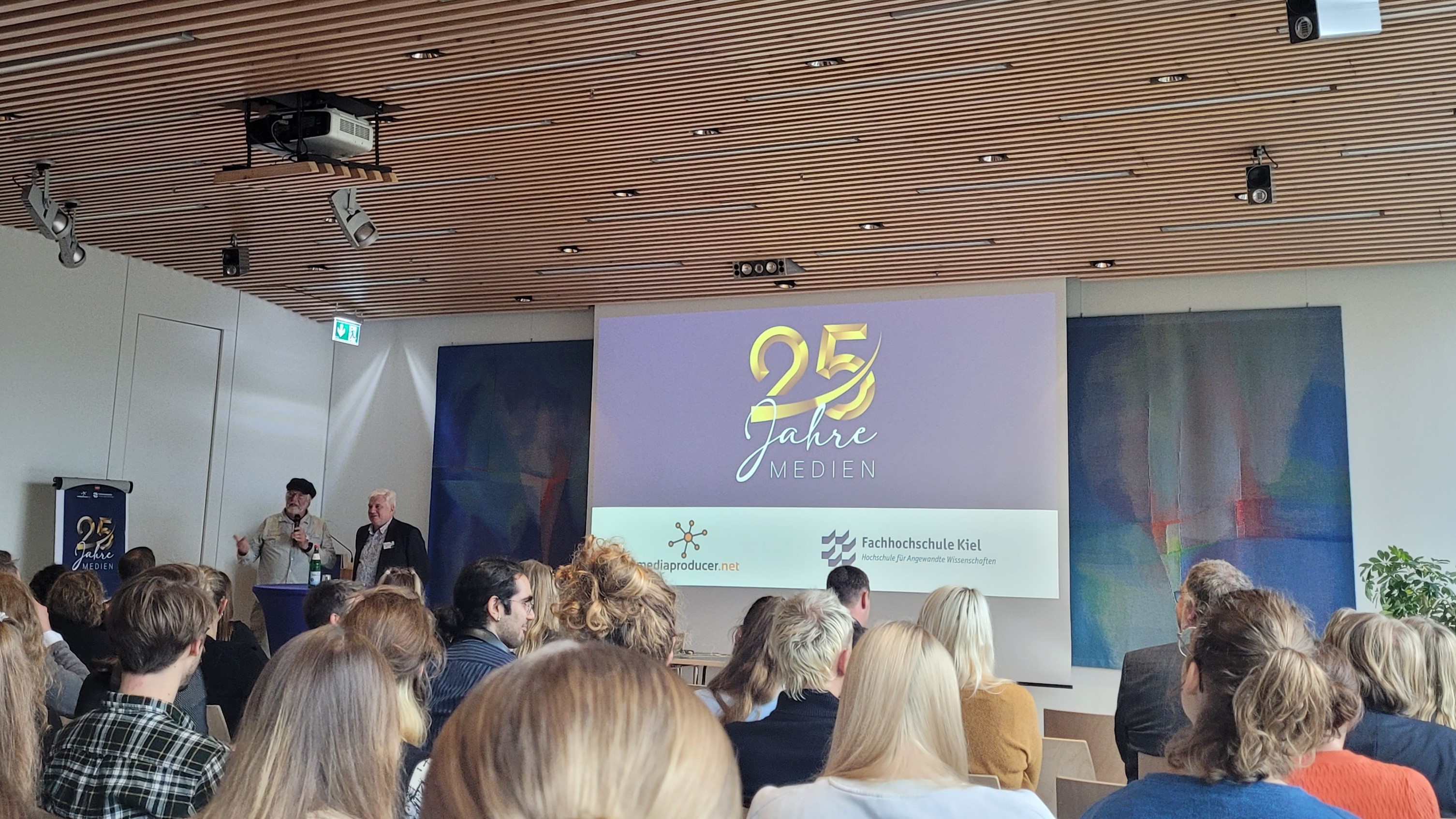 zwei Menschen sprechen vor einem Publikum