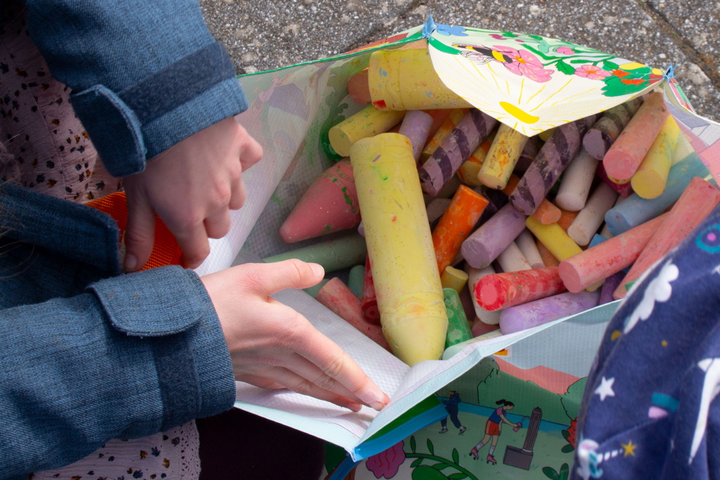 zwei Hände halten eine mit Malkreide gefüllt Tasche auf