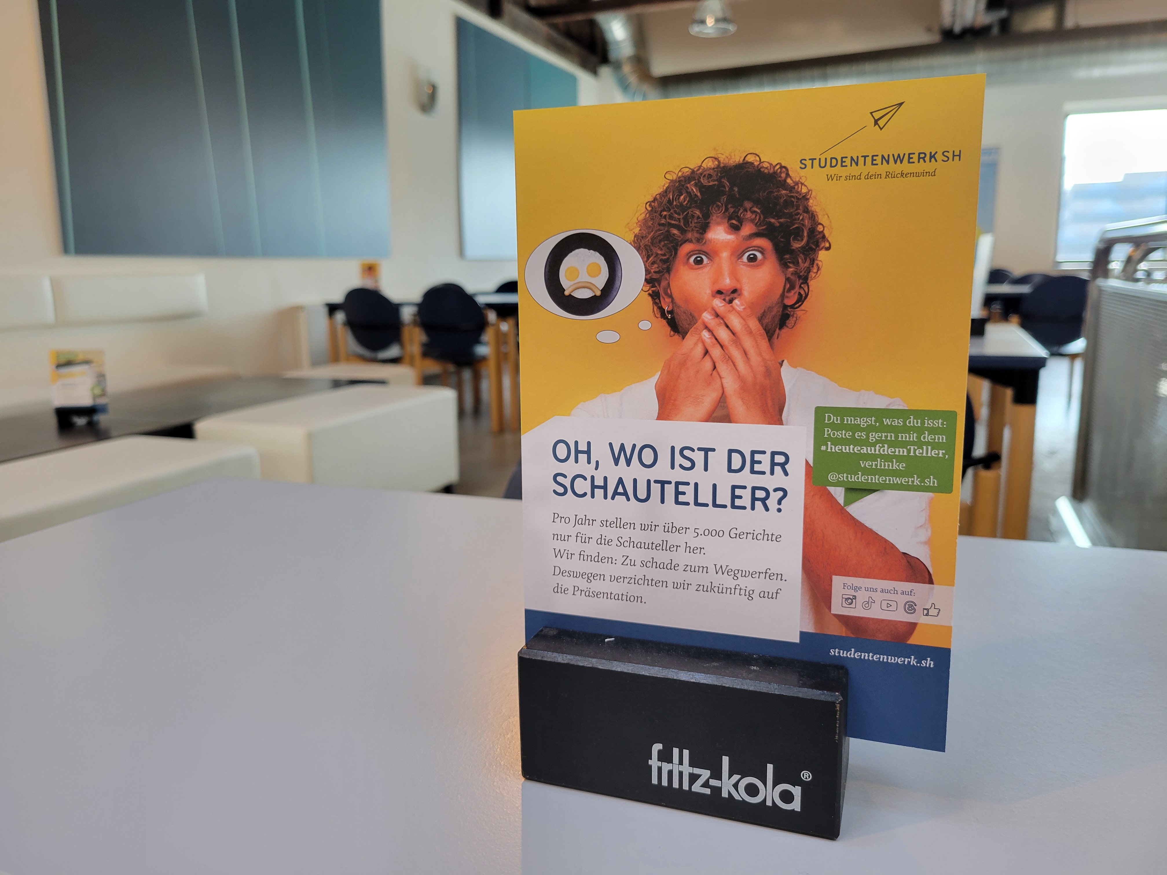 Kleiner Flyer auf einem Tisch in der Mensa. Drauf steht „Oh, wo ist der Schauteller?"