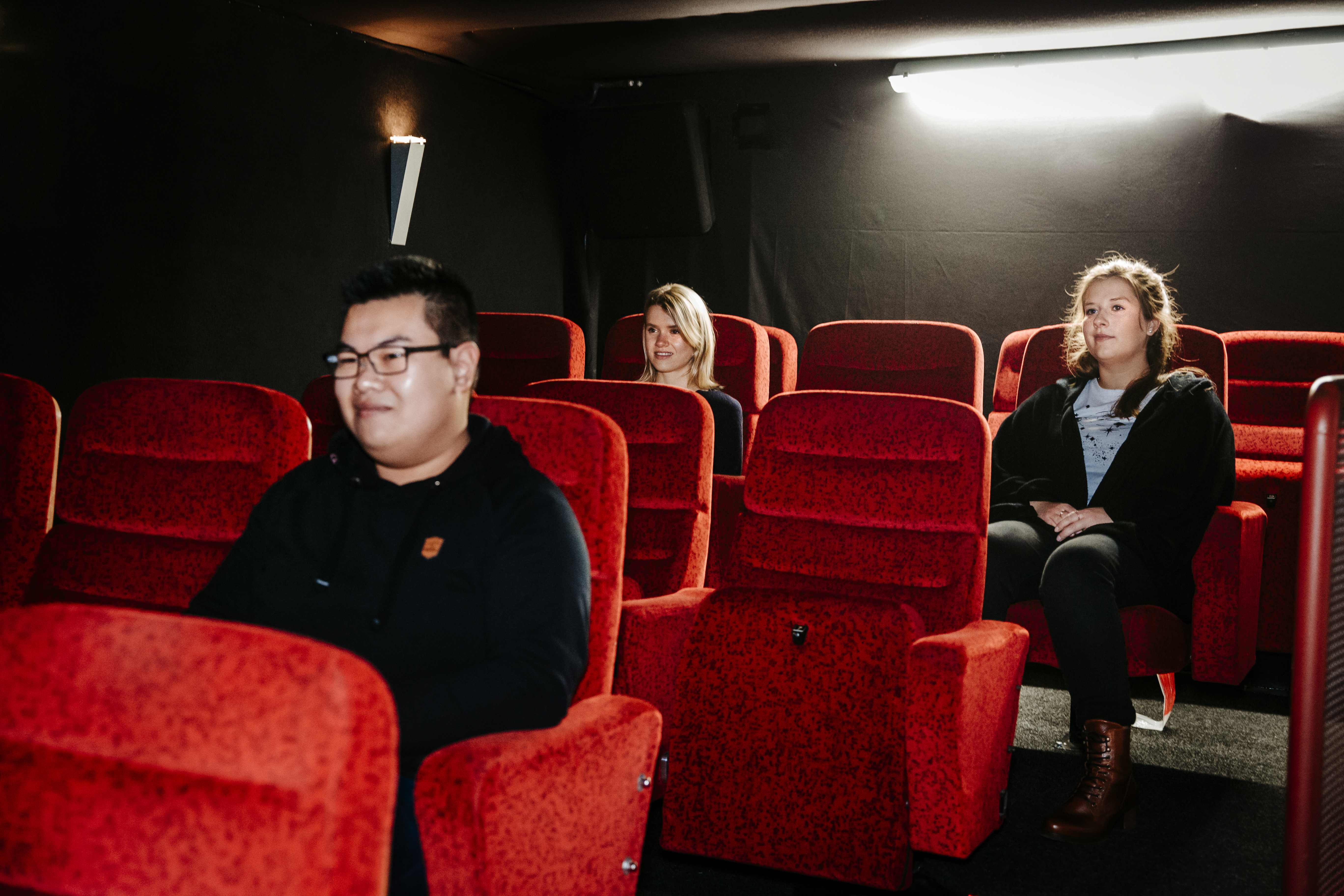 3 Studierende sitzen im Kinosaal des Bunker-D