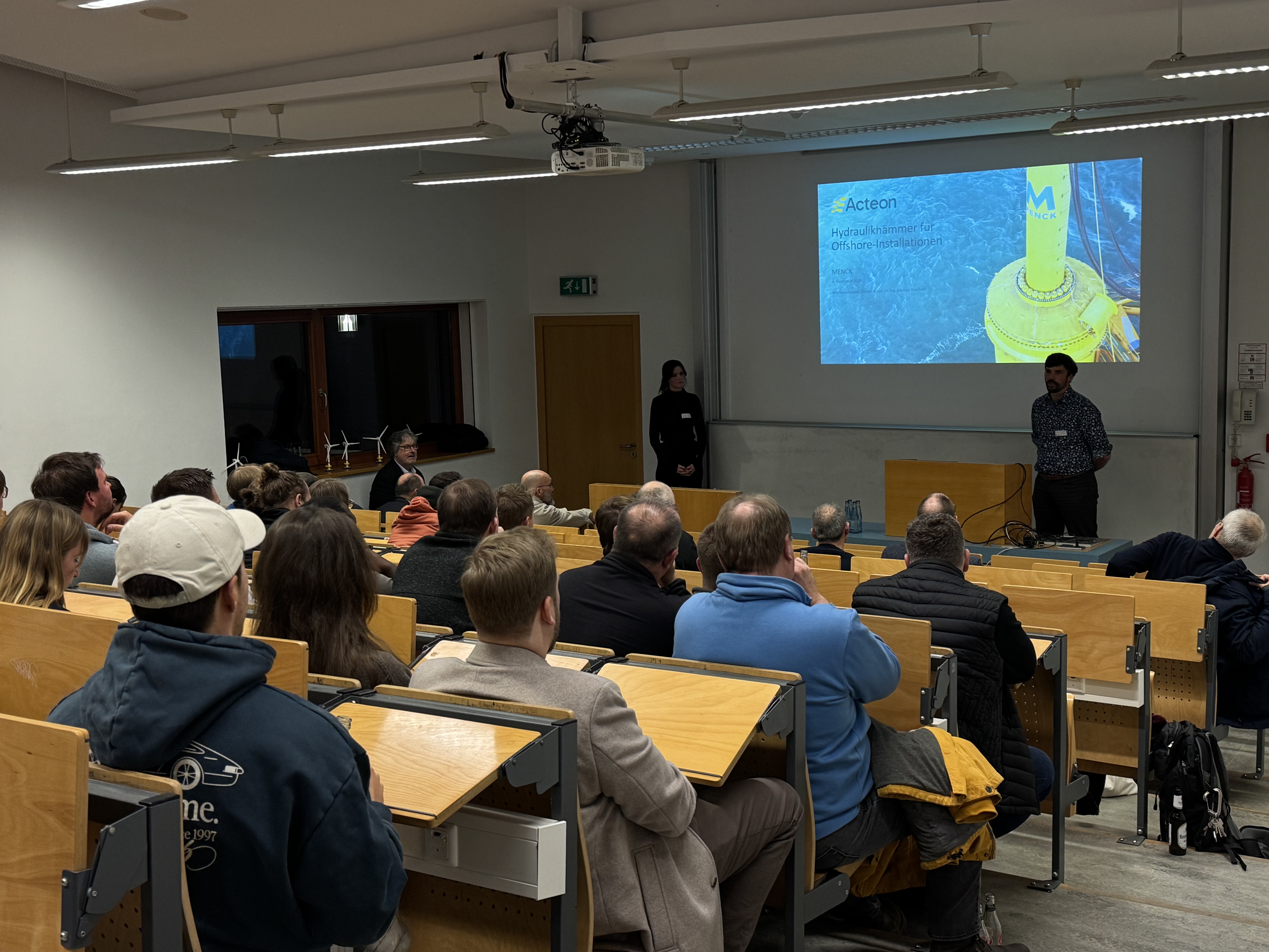 eine Frau und ein Mann stehen in einem Hörsaal vor einer Gruppe Studierender beim 21. Offshore.Club-Abend an der HAW Kiel