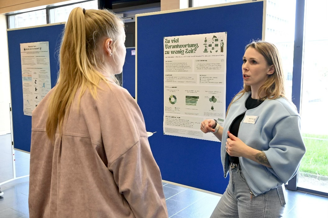 Zwei Frauen sprechen vor einem Poster.
