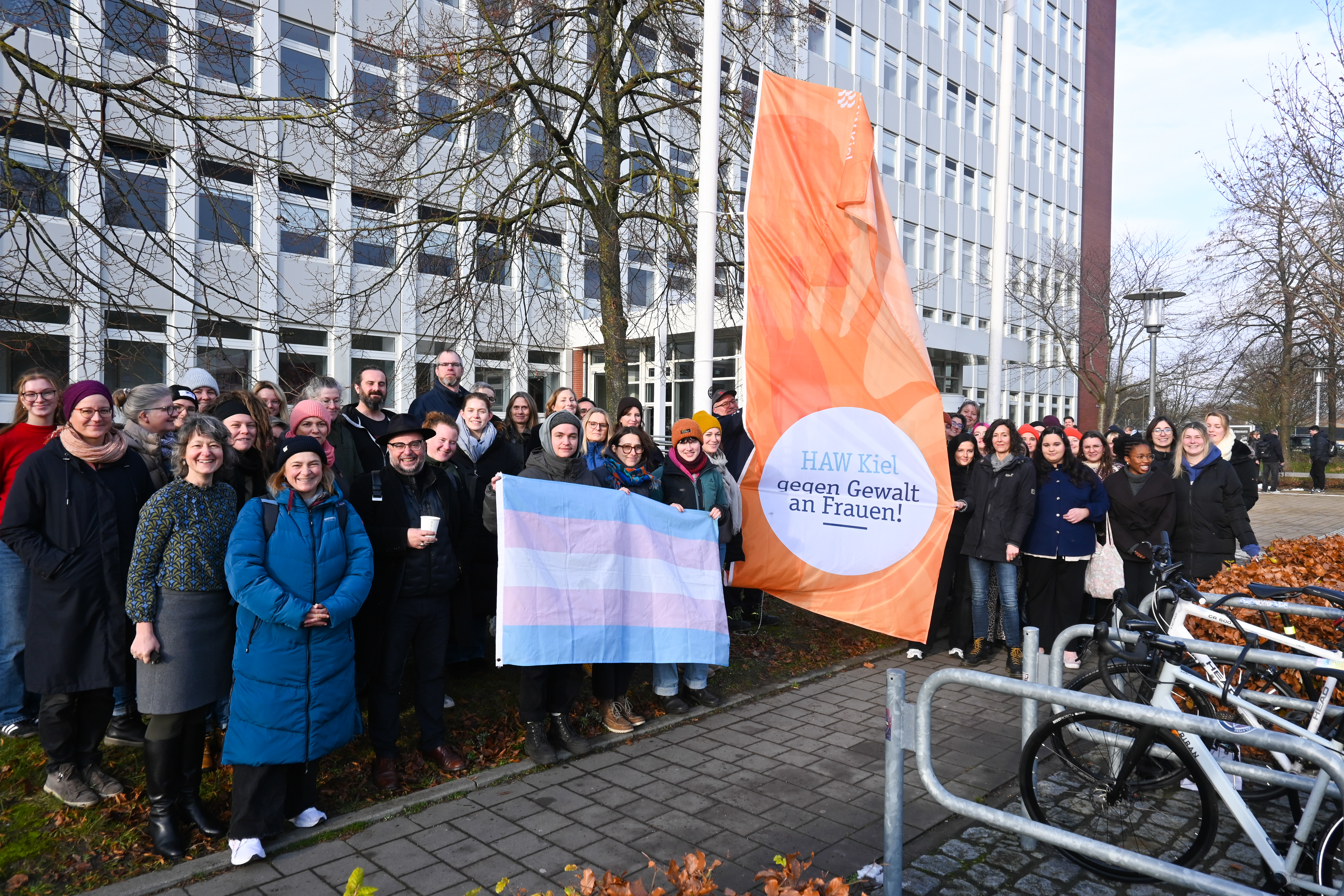 Eine Gruppe von Menschen steht vor einer orangen Flagge.