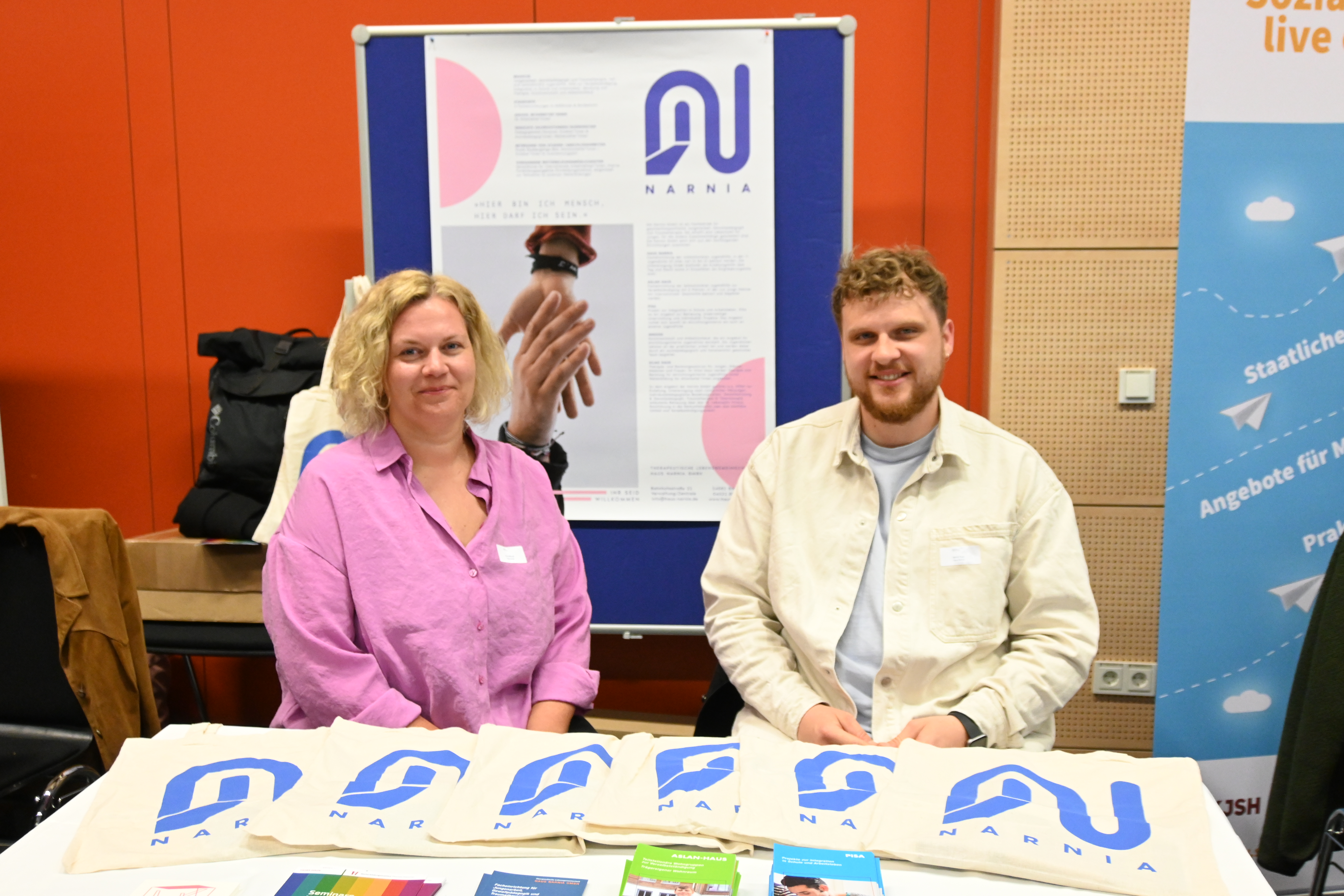 Moritz Puck und Anna Milbradt sitzen an einem Tisch bei der Praxismesse Soziale Arbeit an der FH Kiel