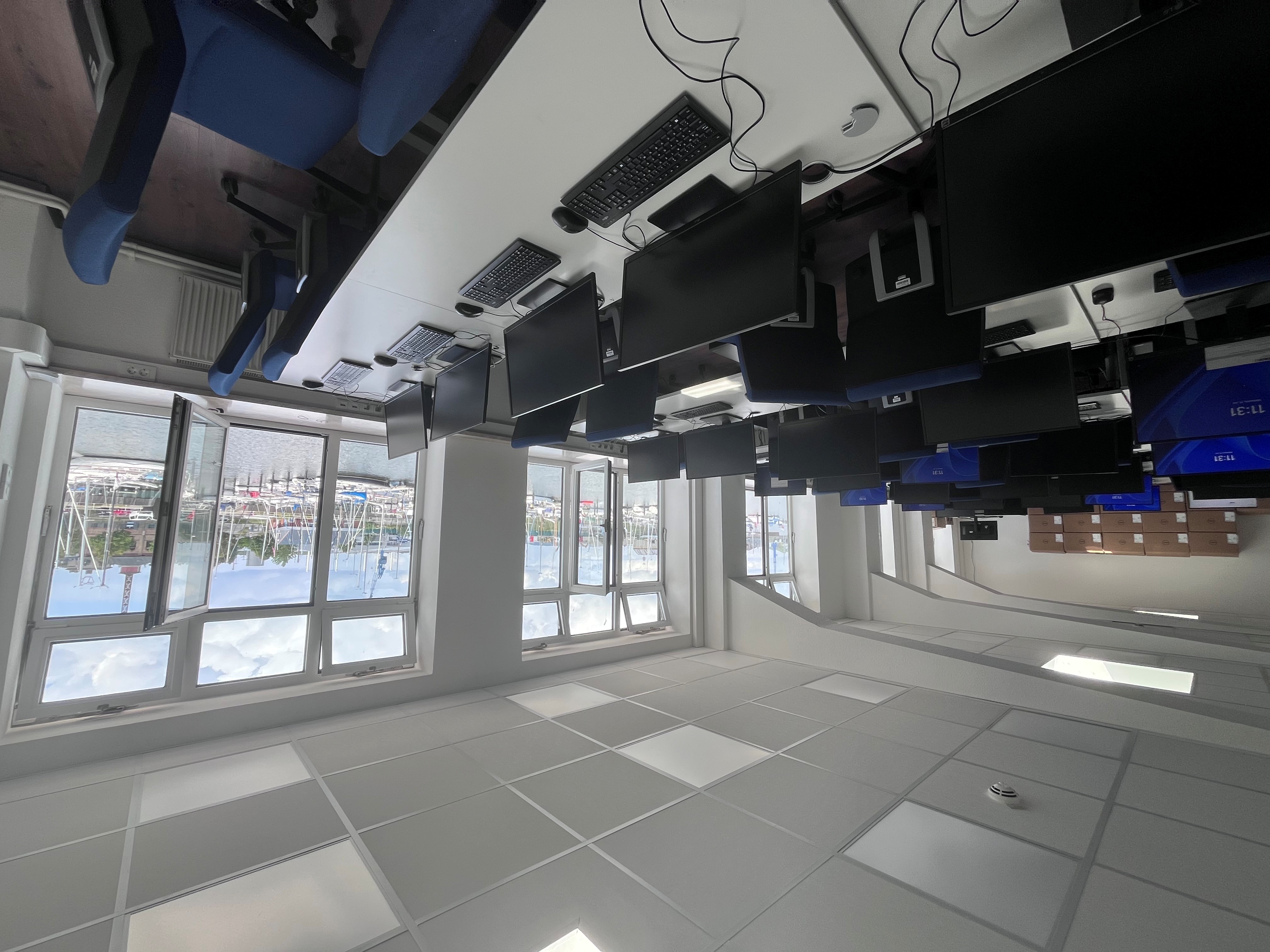 Großer Raum voller Tischreihen auf denen Computerbildschirme stehen