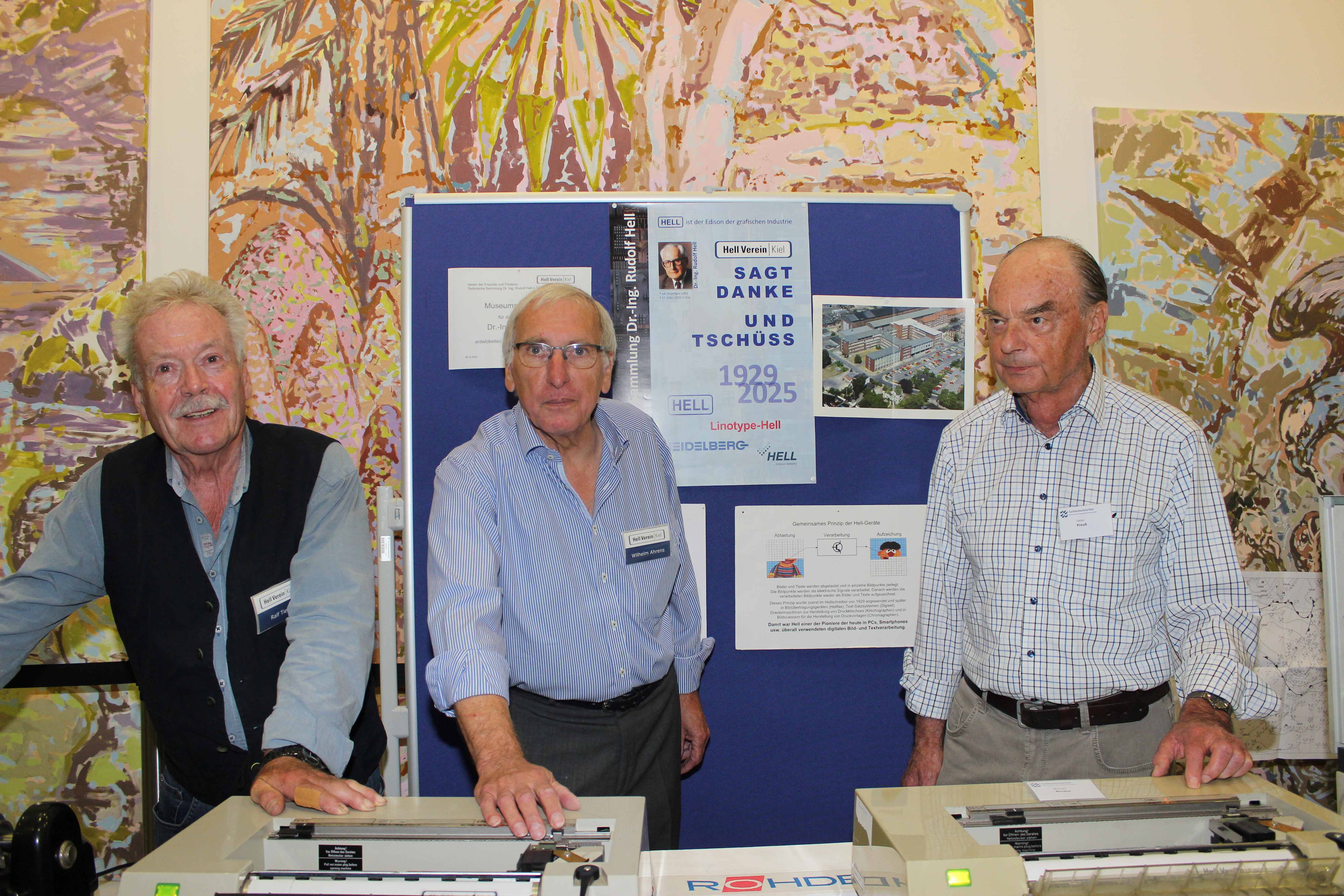 drei Herren vom Hell-Verein an einem Tisch mit alten Fax-Geräten bei der Museumsnacht 2025 an der FH Kiel