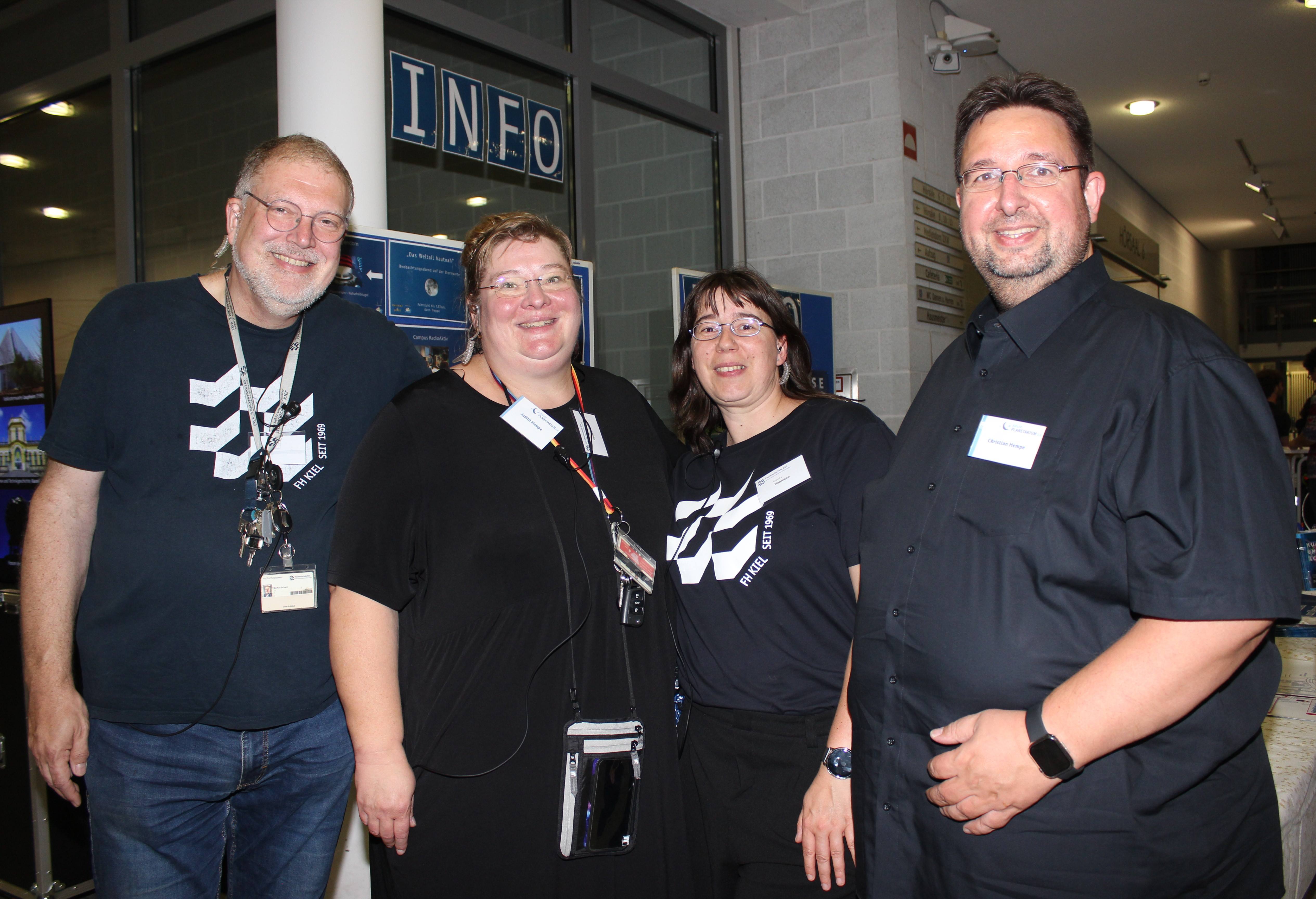 zwei Männer und zwei Frauen aus dem Orga-Team der Museumsnacht 2025 an der FH Kiel vor dem Infostand