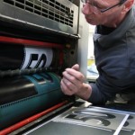 Ein Mann schaut prüfend in eine Druckerpresse.