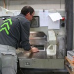 Ein Mann führt etwas in die Druckerpresse ein.