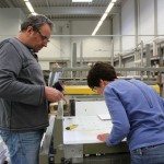 Ein Mann und eine Frau prüfen etwas auf der Druckerpresse.