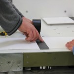 Männerhände kleben einen Streifen dickes Klebeband auf eine Stellfläche.