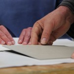 Drei Hände präparieren einen Druck.