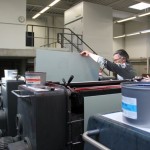 Ein Mann setzt einen Bogen Papier in die Druckerpresse ein.