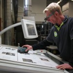 Ein MAnn an einem Zeichentisch prüft die Drucke auf Korrektheit.