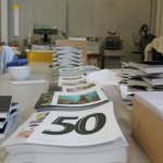 Auf einem Tisch liegen mehrere Stapel des Druckwerks.