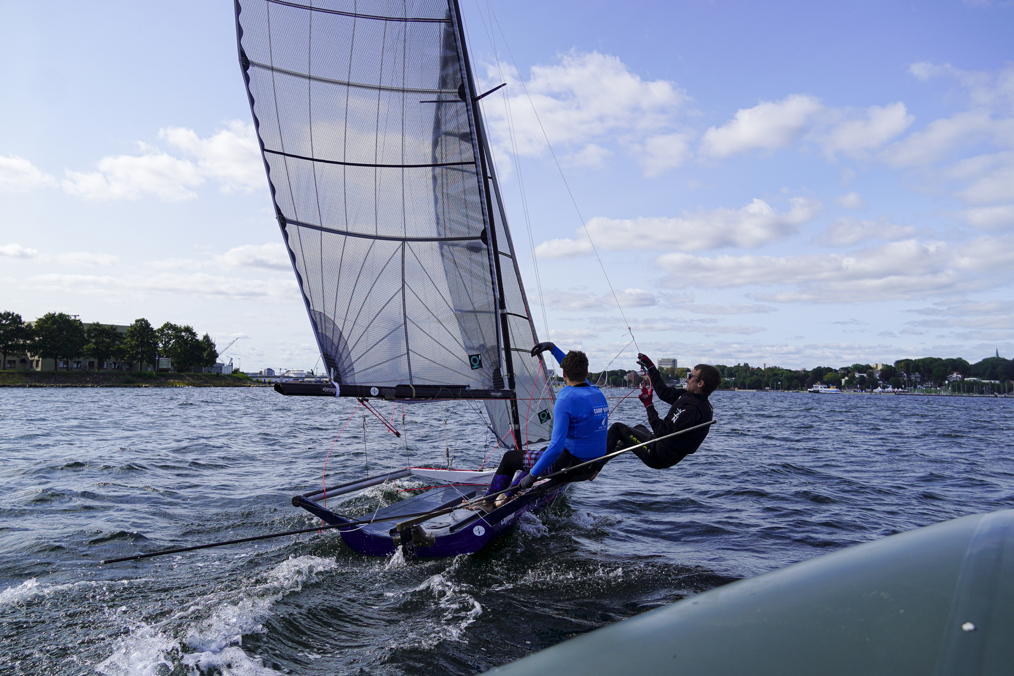 Zwei junge Männer segeln auf der Kieler Förde.
