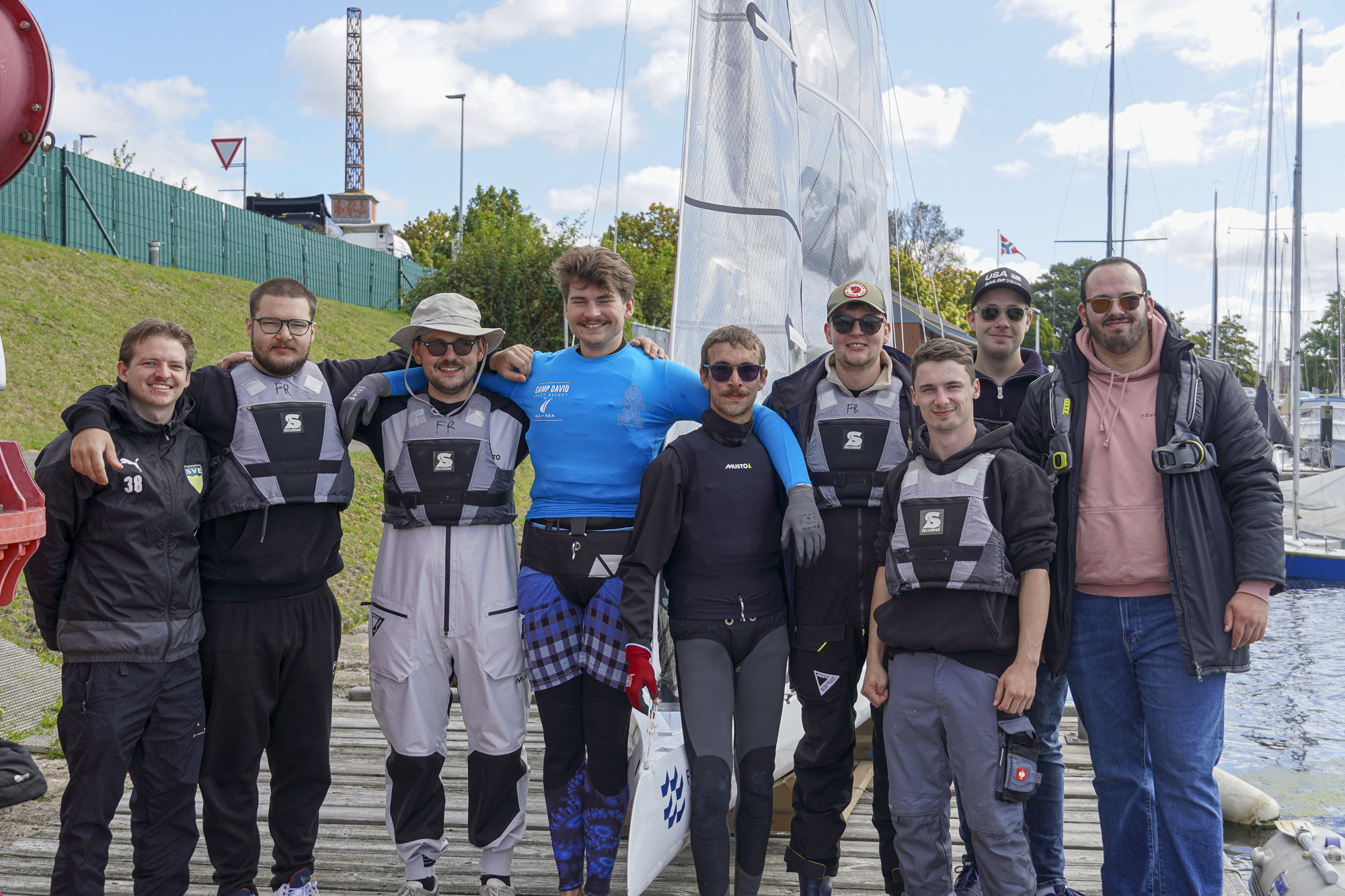 Gruppe junger Männer in Segelkleidung auf Steg