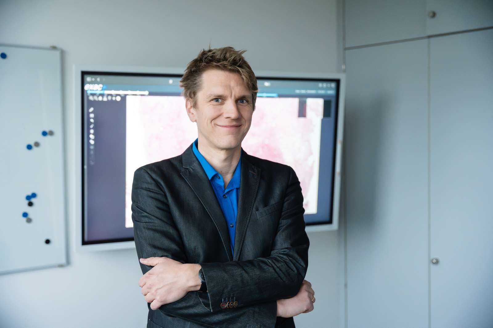 Auf dem Bild ist ein Portrait von Marc Aubreville zu sehen. Er hat die Arme verschräntk und lächelt in die Kamera.